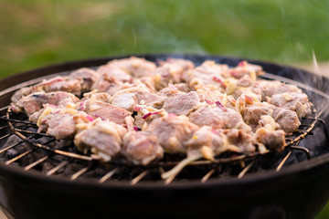 Grilling barbeque meet on the grill outdoors in the back yard. Summer time picnic. Roasting meat on metal grid on hot coals. Smoke adds a smoky flavor