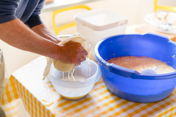 Making of Cepelinai - Zeppelins is national Lithuanian dish. Mans hands draining grated potatoes. Squeezing gauze with potatoes inside to separating juice from vegetables to get dry mash