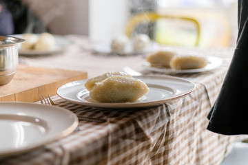 Making of Cepelinai - Zeppelins is national Lithuanian dish. Serving hot zeppelins on a plate at home © CrispyMedia