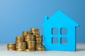 House and stack of coins. The concept of buying home or insurance. Blue background.