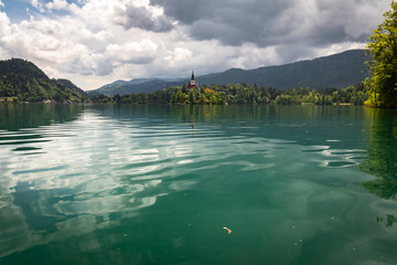 beautiful view on famous bled lake with church on island in stormy sky in julian alps, slovenia