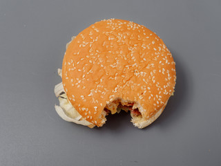 bitten big burger with cutlet cheese and tomato on a gray background