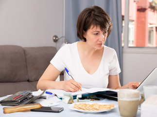Woman with documents while working at laptop at home