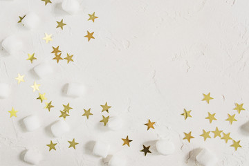 Festive white background with mini marshmallows and golden confetti stars. Greeting card with copy space
