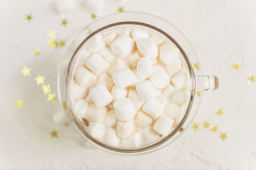 Fototapeta na wymiar top view of cup of hot delicious cocoa drink with marshmallows on gold stars background