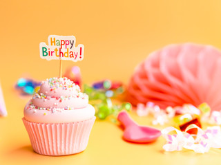 Pink cupcake with Happy Birthday text on beige background