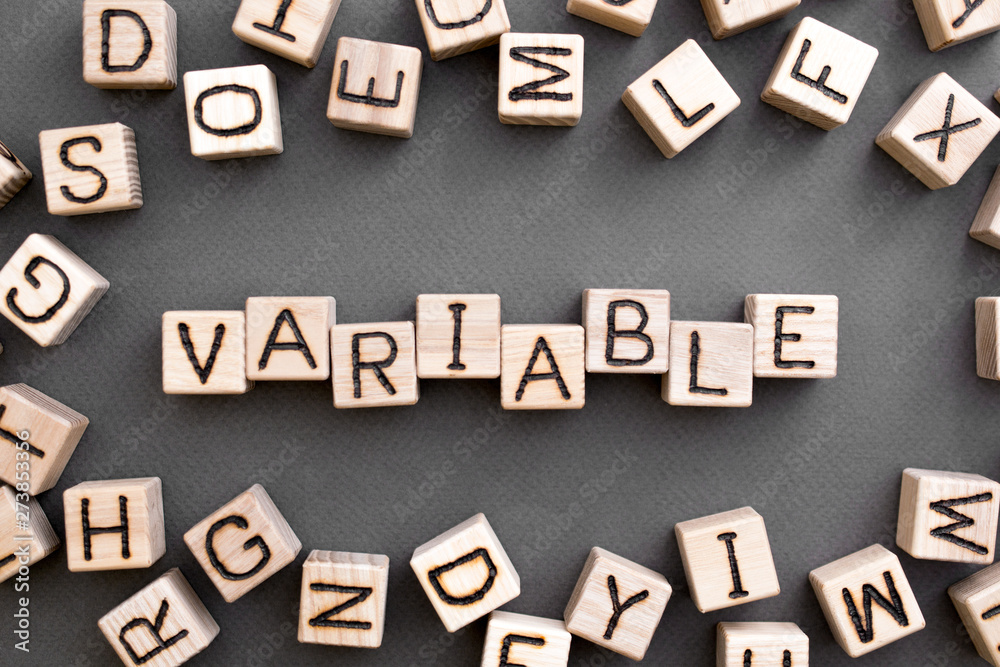 Fototapete the word variable wooden cubes with burnt letters, variable life, gray background top view, scattere