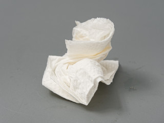 Fototapeta na wymiar crumpled used white paper napkin on a gray background