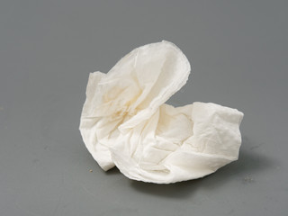 crumpled used white paper napkin on a gray background