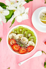 Healthy breakfast bowl smoothie with strawberry, banana, kiwi  and chia seeds on pink background. Healthy vegan food concept..