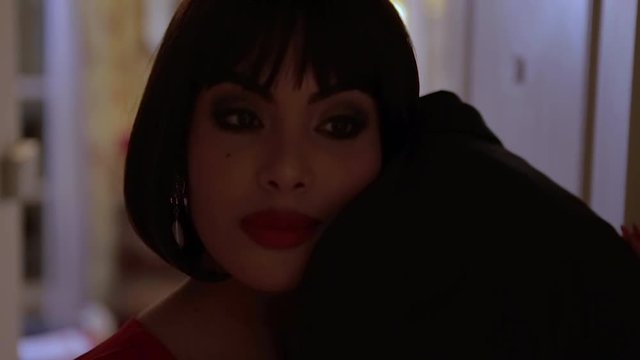Deceived Sexy brunette Arab wife in tight red dress hugging her husband at the door of a room in a retro hotel with walls adorned with floral tapestry. Slow motion beauty couple concept. Cheated.