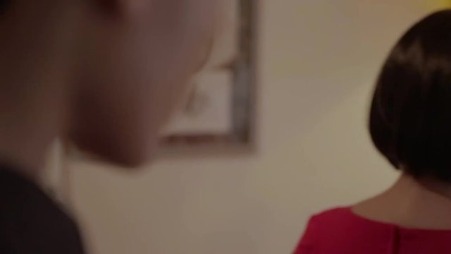 Sexy brunette Arab wife in tight red dress discovering that her husband is cheating on her in room of a retro hotel with walls adorned with floral tapestry. Slow motion beauty couple concept. Cheated.