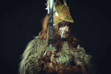 Viking, Scandinavian warrior with helmet and war paintings, wears a sword and a cape of animal skin