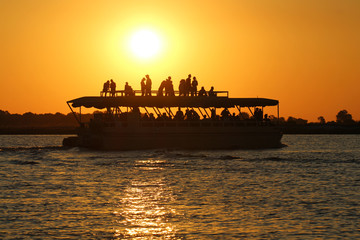 Menschen stehen auf Boot im Sonnenuntergang