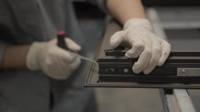 Worker screwing a window, drill macro, processing of aluminum parts in a Production of aluminium Windows Workshop. Manufacturing of plastic double-glazed windows. Factory for PVC windows and doors.