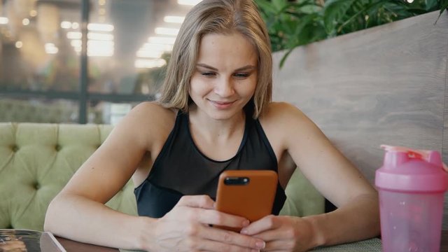 Woman texting message on her smartphone inside cafe