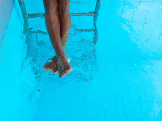 adult Afro American man's legs underwater in swimming pool