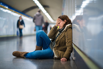 Young depressed woman crying on the ground on subway underground