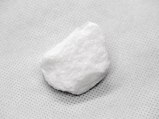 Geological specimen of natural white layered mineral Calcite - semiprecious stone, on white background
