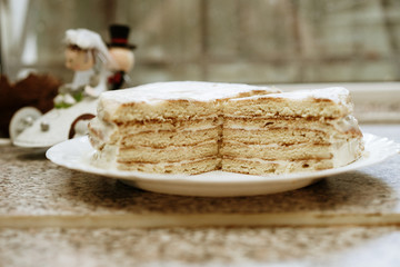 homemade honey cake in the cut. bride and groom in the background. selective focus