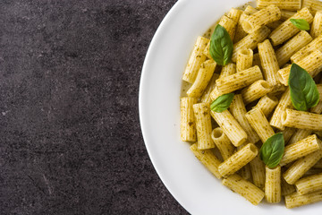 Penne pasta with pesto sauce on black background. Top view. Copyspace