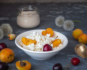 Light morning lunch for a fitness girl with cottage cheese, sour cream in a glass jar and fresh berries on a gray background