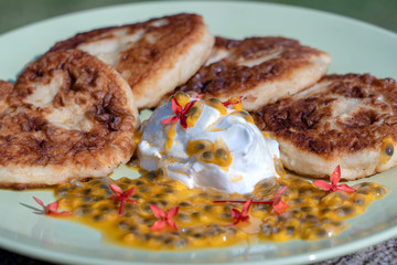 Cheesecakes with passion fruit and sour cream in a green plate for breakfast. Delicious dessert, closeup