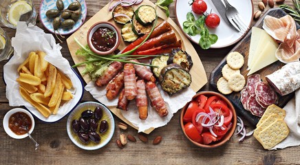 Grill party table concept with grilled sausage, potato fries,vegetable,sappetizers and tomato salad. Summer outdoor dinner table .