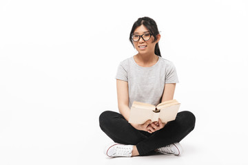 Beautiful young woman posing isolated over white wall background holding book reading.