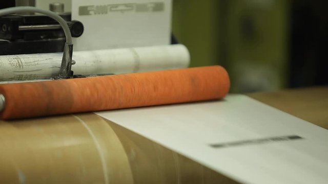 Orange Label Printing Rolls with High speed labeling machine in industrial factory, sticker on product in manufacture. Flexible packaging. Close-Up Macro.