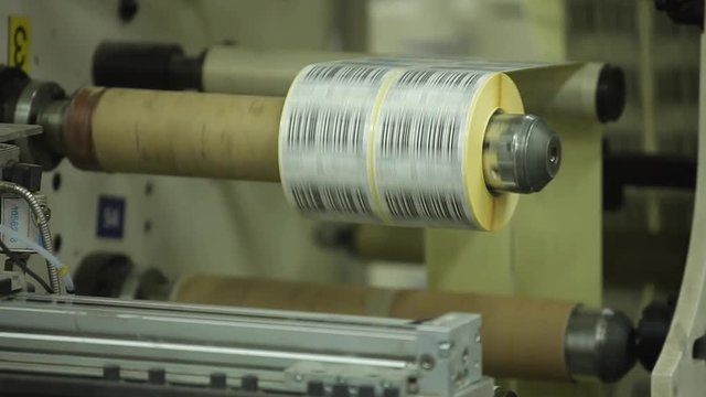 Multi Label Printing Rolls with High speed labeling machine in industrial factory, sticker on product in manufacture. Flexible packaging. Close-Up Macro.