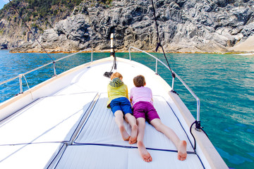 Two adorable school kid boys, best friends enjoying sailing boat trip. Family vacations on sea on...