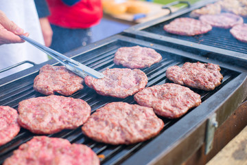 Barbecue in the garden. A man scoops burgers. Close-up.