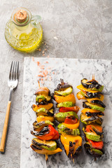 Grilled vegetable skewers on the gray stone background