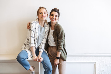 Cheerful girls standing at white wall