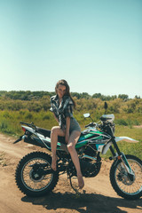 Young beautiful girl posing sitting on a motorcycle outdoors