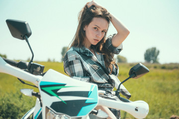 Fototapeta na wymiar Young beautiful girl posing next to a motorcycle outdoors
