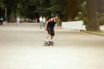 Skateboarder doing a trick at the city's street in cloudly day. Young man in sneakers and cap...