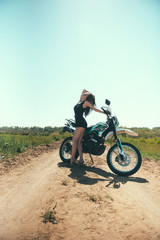 Fototapeta na wymiar Young beautiful girl posing next to a motorcycle outdoors