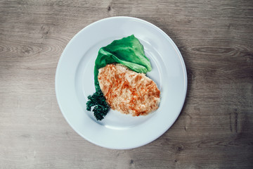 chicken fillet in cheese and lettuce on a white plate