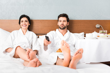 Fototapeta premium selective focus of cheerful man holding remote controller near attractive woman in hotel room