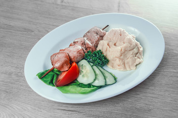 mashed potatoes and kebab on a wooden skewer in a white plate
