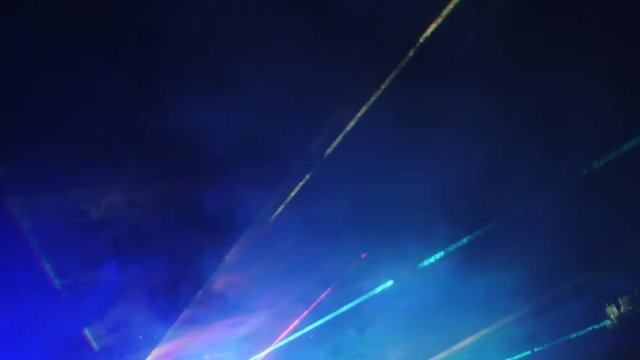 Laser show in a nightclub under the open sky. Laser beams and strobe lights in the night sky.