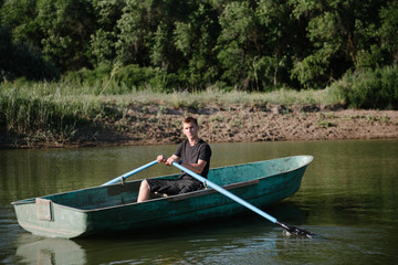 Young man floats on a wooden boat with oars © bo.kvk