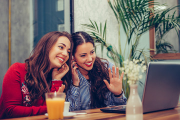 Young woman waving hand and talking while having a video call with their friends on a laptop