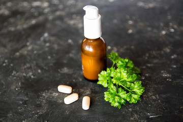 Brown bottle, tablets and herbs on the texture table.