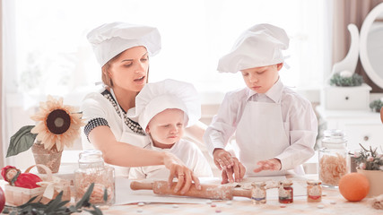 happy mother teaches her children to cook delicious food