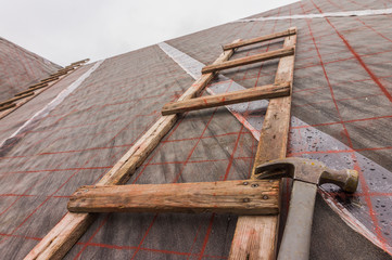 Dachdeckerleiter und Latthammer auf Dach mit Dachpappe und Markierungen authentisch