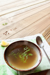 top view slow beef broth soup bowl served with fresh dill and lemon on table-napkin wooden table background with copy space