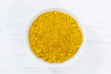 Curry powder spice from above bowl wooden board